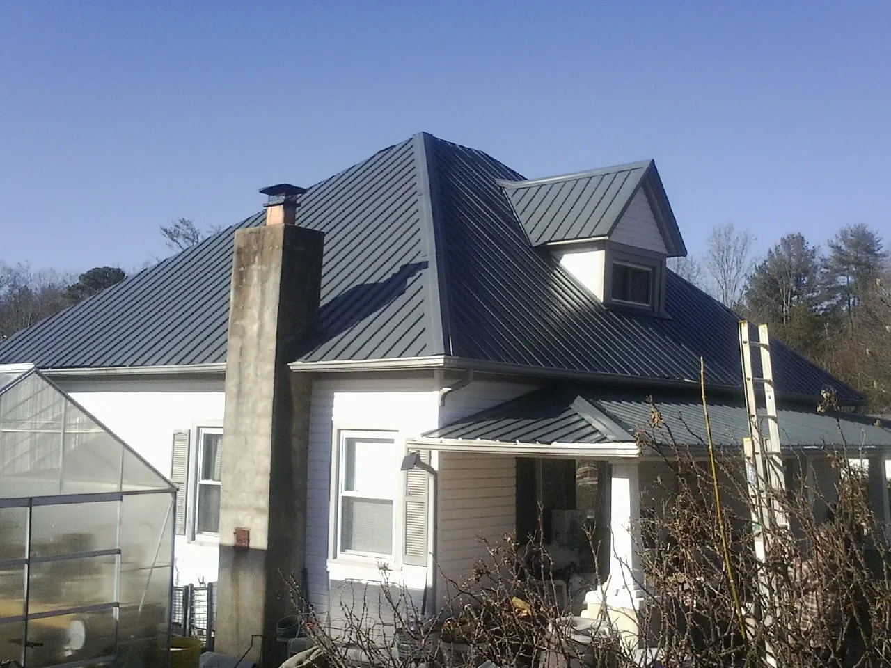 Dark blue standing seam metal roof on a white farmhouse with dormer — Slate & Tile Roof Repair by Roofing Brothers in Bradley Beach