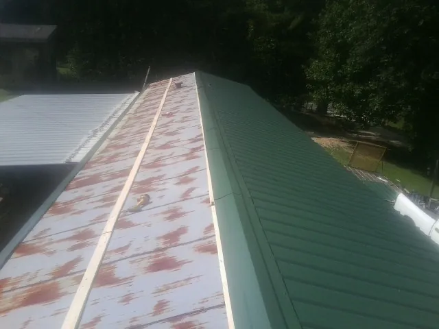 Old rusted panels beside newly installed green metal roofing — Wind Damage Roof Repair by Roofing Brothers in Bradley Beach