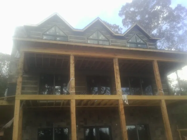 Dormers and porch framing on a large log home under construction — Roof Coating work by our crew in Bradley Beach