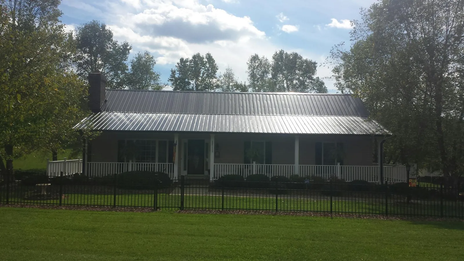 Gray metal roof on a brick ranch with a full width front porch — Gutter Guard Installation work by our crew in Bradley Beach