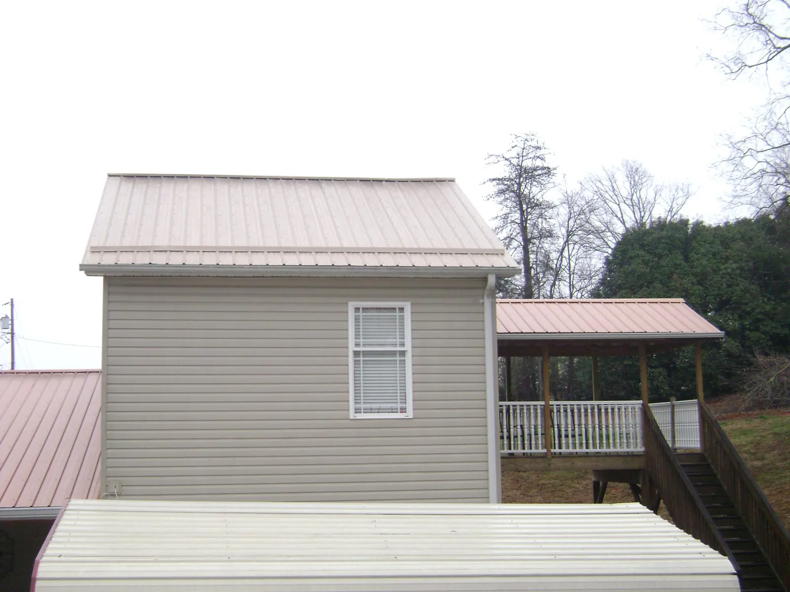 Tan metal roofs on a two story addition and attached porch, from a Roof Replacement job in Bradley Beach