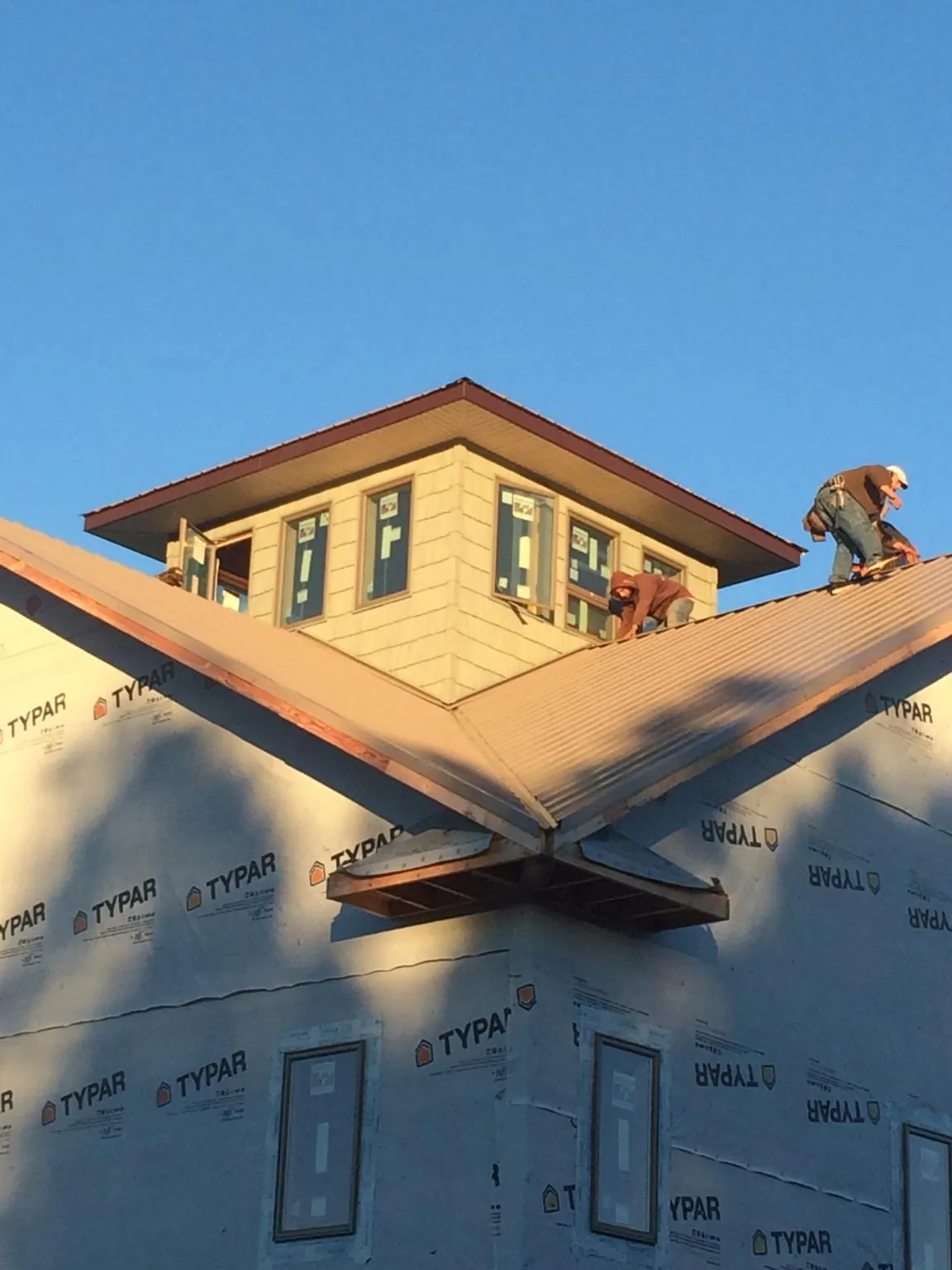 Roofers working around a rooftop cupola on a new metal roof at sunset — Roof Waterproofing in Bradley Beach by Roofing Brothers